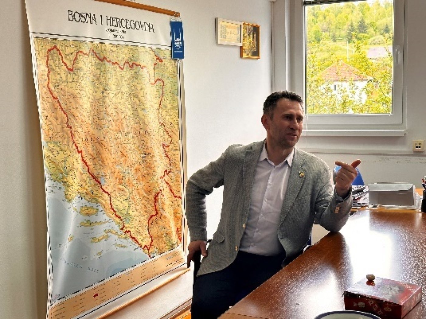 Emir Cica, Country Director of Islamic Relief Bosnia and Herzegovina, speaking in an office beside a large wall map of Bosnia and Herzegovina.