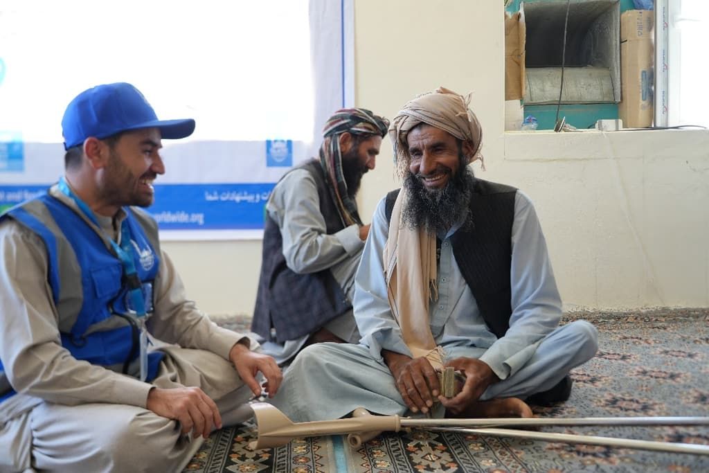 An Islamic Relief team member sits with an elderly man during a cash assistance distribution in Balkh province, Afghanistan.