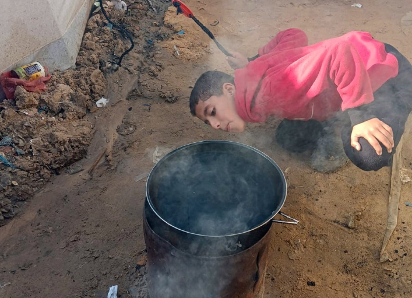 A boy tends a large cooking pot at a community kitchen in Gaza.