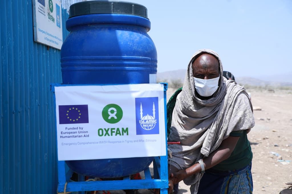 A woman collects water from a large blue tank at a water point in northern Ethiopia.