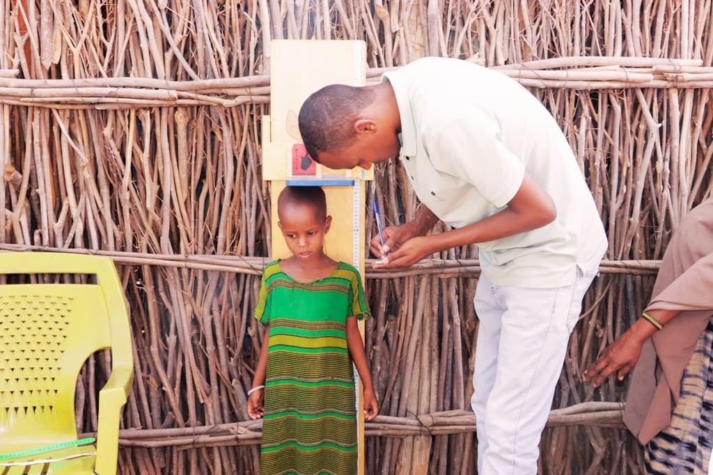 A health worker measures a young child’s height during a community malnutrition screening in Wajir County, Kenya.