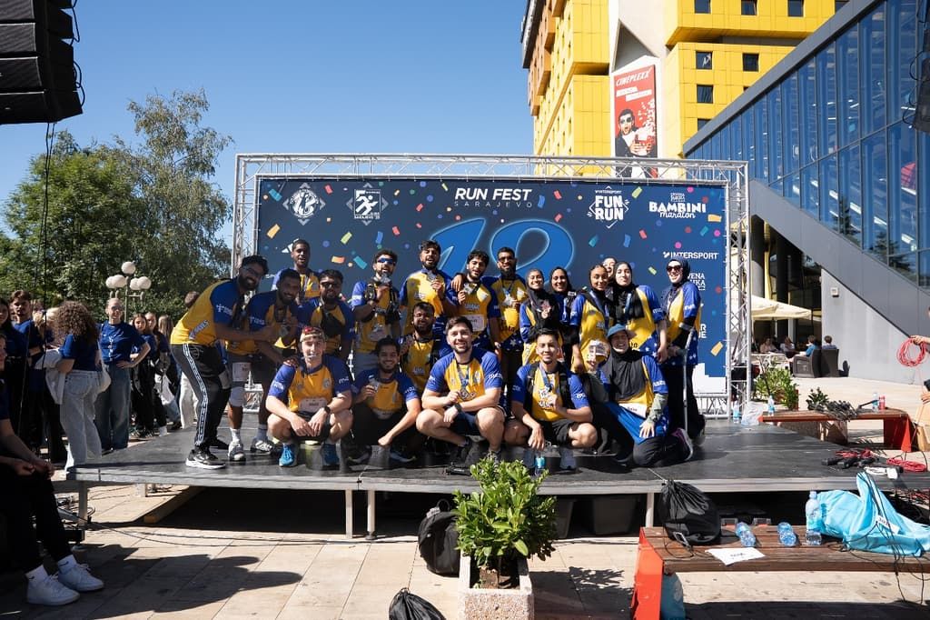 A team of Islamic Relief runners in blue and yellow kit pose together on a stage at a marathon event.