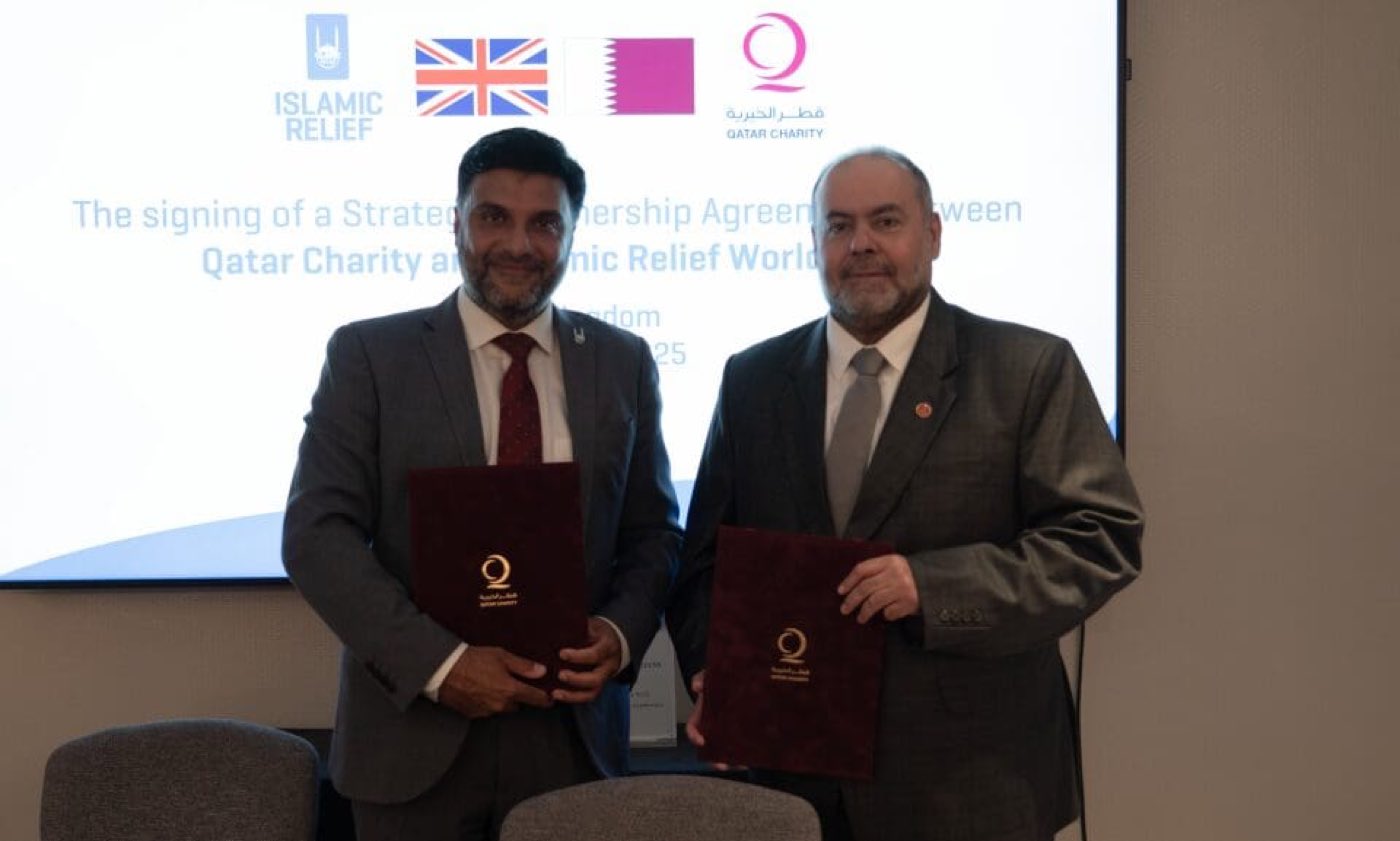 Representatives of Islamic Relief Worldwide and Qatar Charity holding signed copies of their three-year agreement.